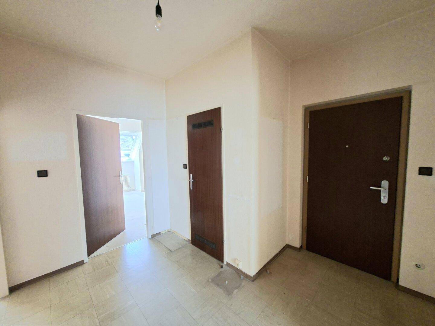 Eingangsbereich mit Fliesenboden und mehreren Türen, eine davon zur Wohnungstür.