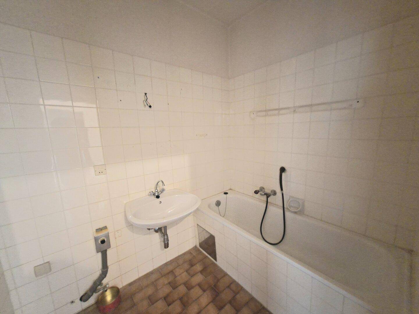 Badezimmer mit Badewanne, Waschbecken und weißen Fliesen, im Originalzustand.
