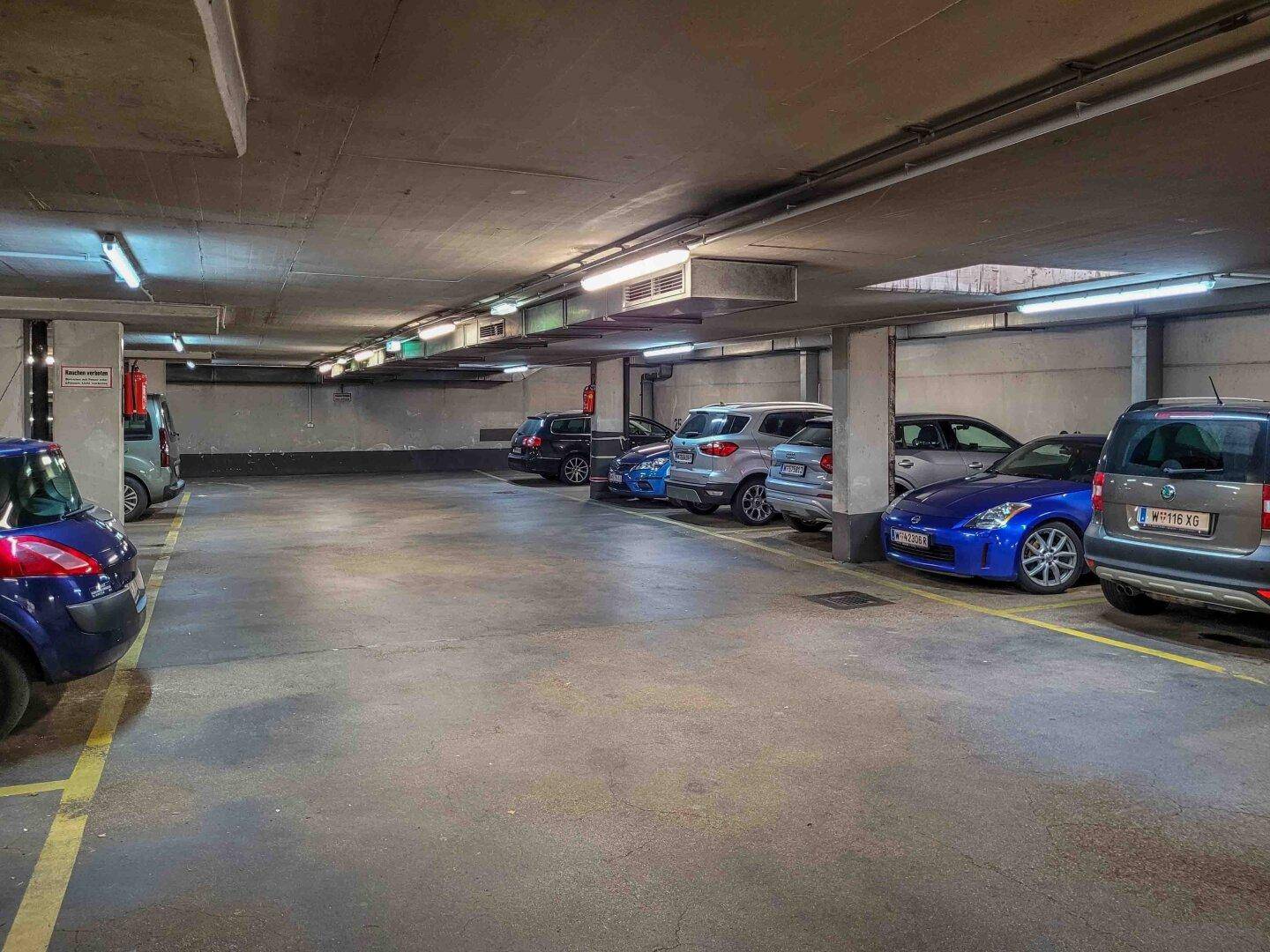 Tiefgarage mit mehreren Stellplätzen und geparkten Fahrzeugen.