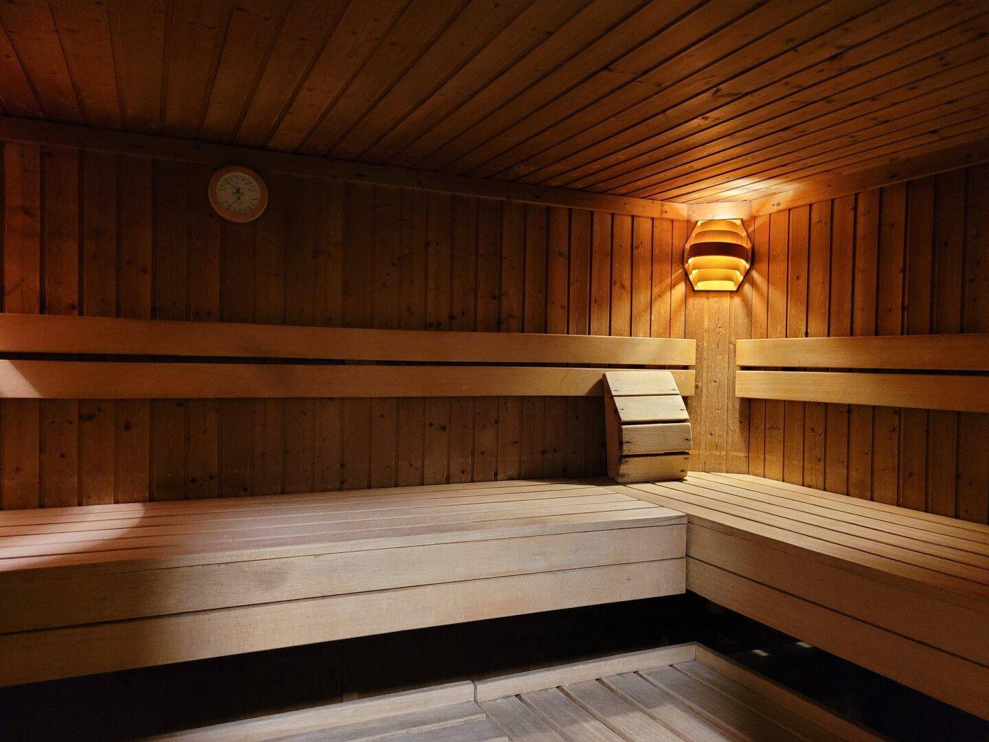 Gemütliche Holzsauna mit Bänken und warmer Beleuchtung für entspannende Momente.