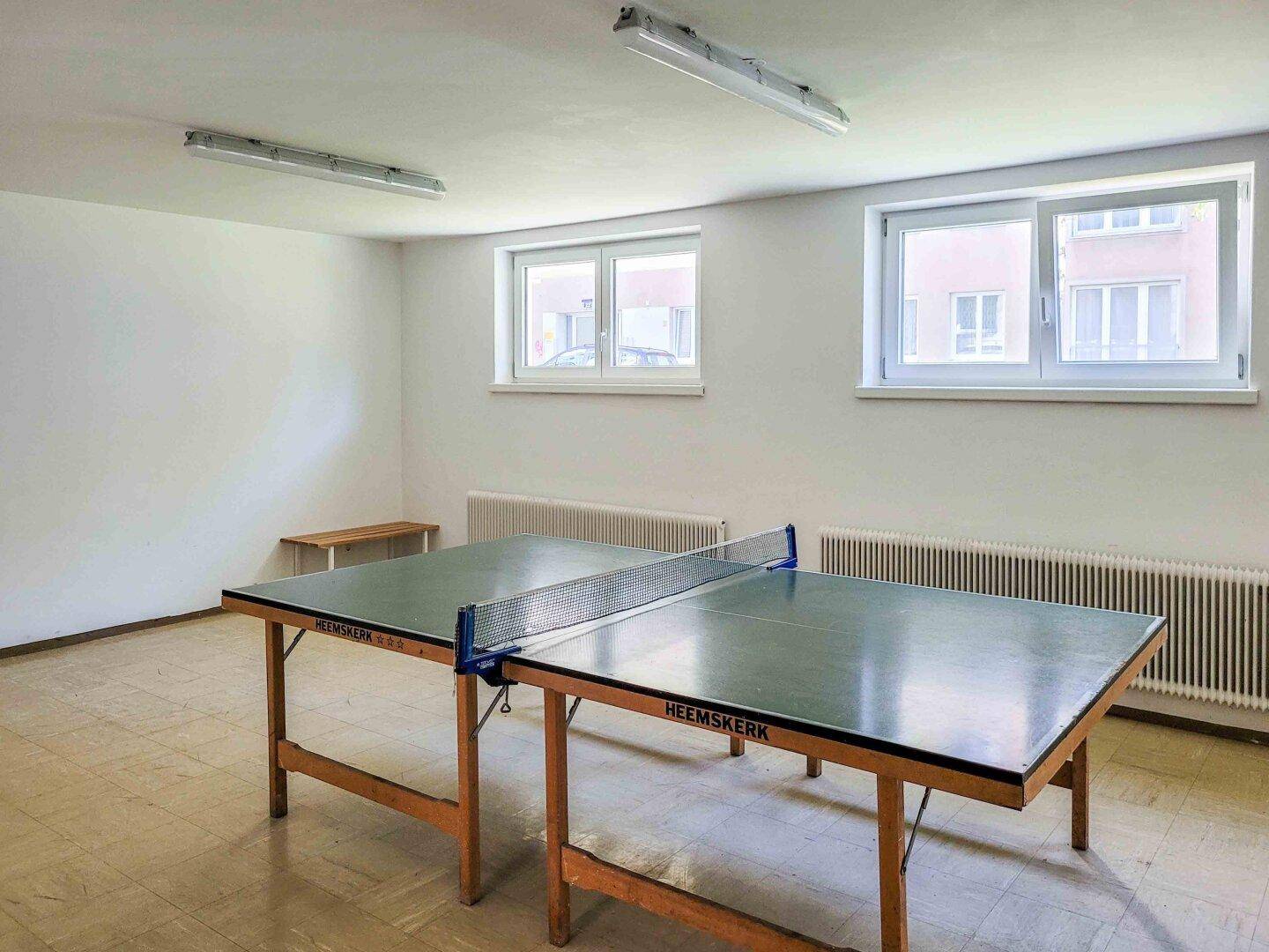 Gemeinschaftsraum mit Tischtennisplatte und Fenstern, ideal für Freizeitaktivitäten.