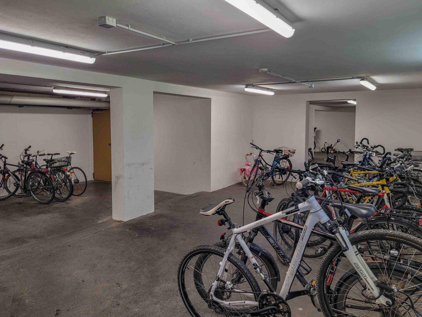 Geräumiger Fahrradraum im Untergeschoss mit vielen abgestellten Fahrrädern und Beleuchtung.