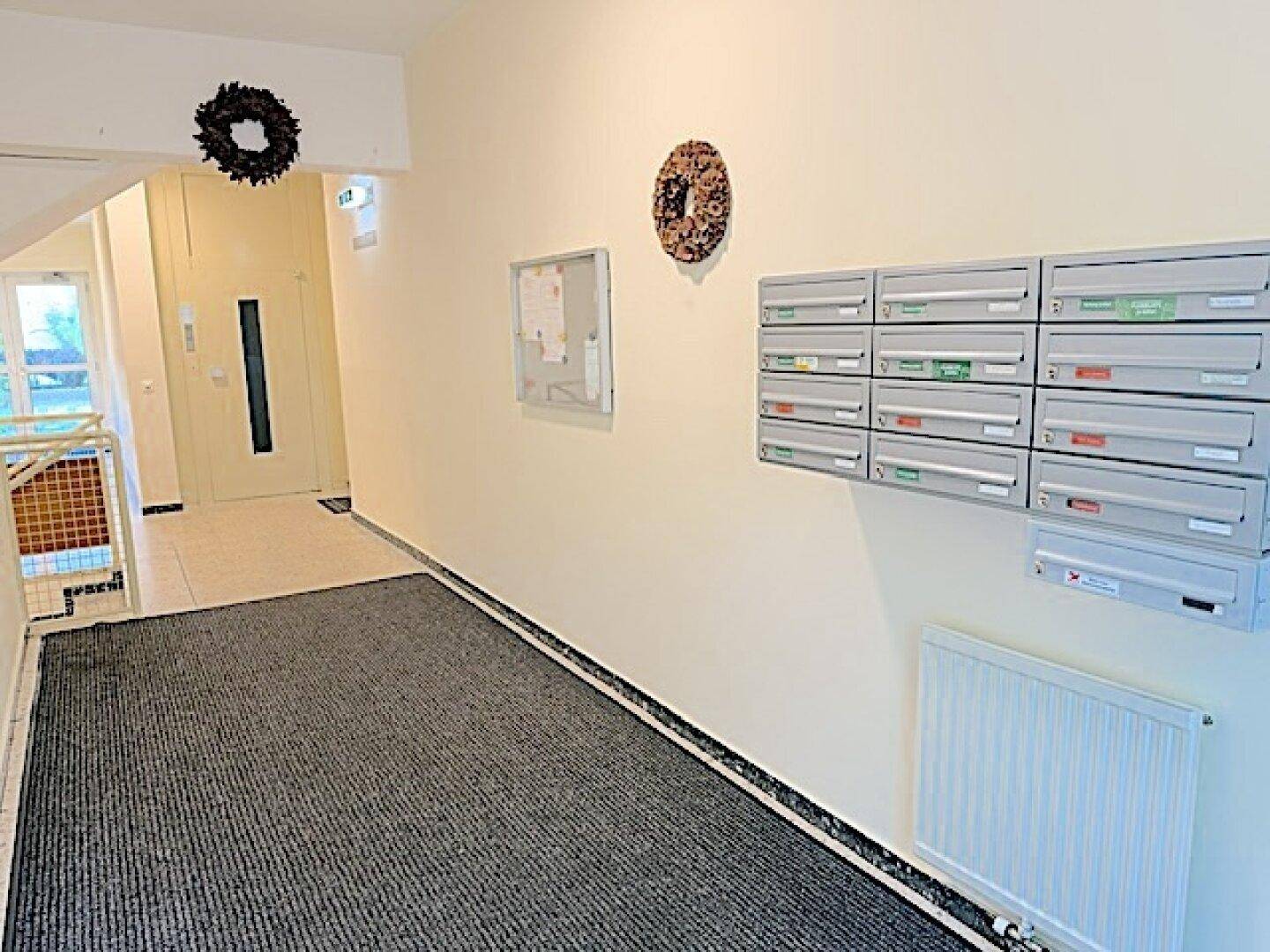 Eingangsbereich des Gebäudes mit Briefkästen und Teppichboden.