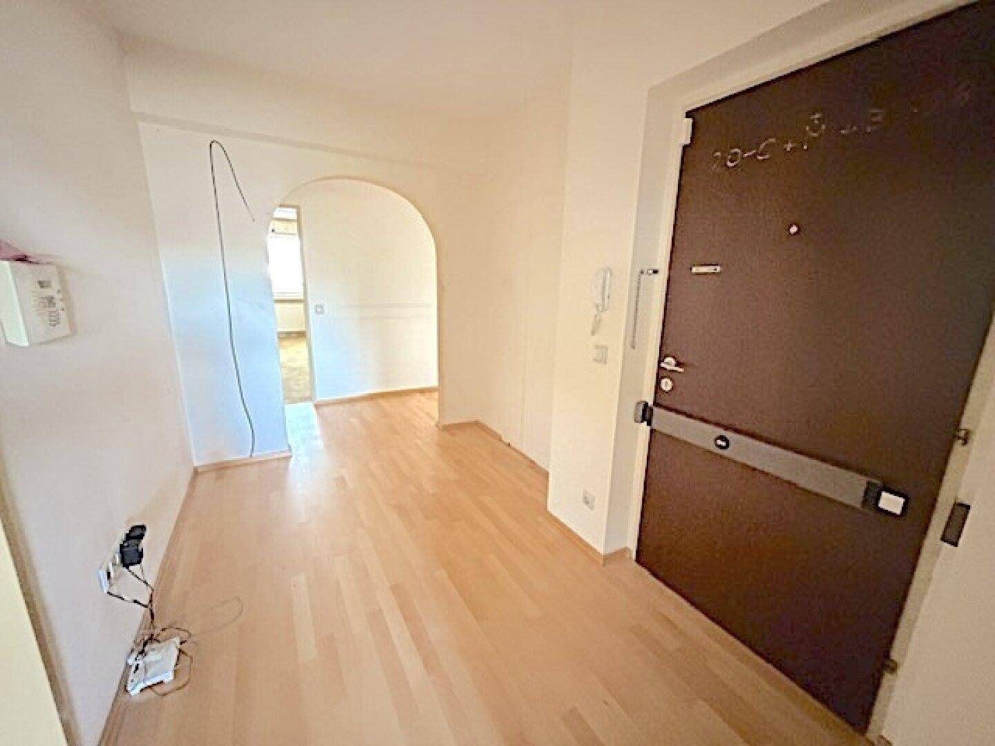Heller Flur mit Holzboden und einem Bogen, der zu weiteren Räumen führt.