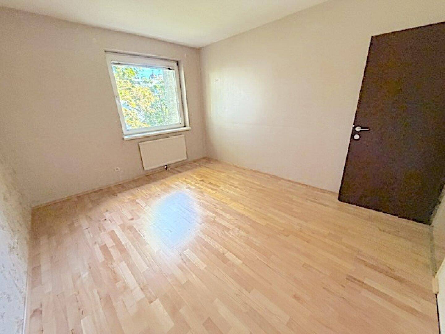 Helles Zimmer mit Holzboden und Fenster, ideal als Schlaf- oder Arbeitszimmer.