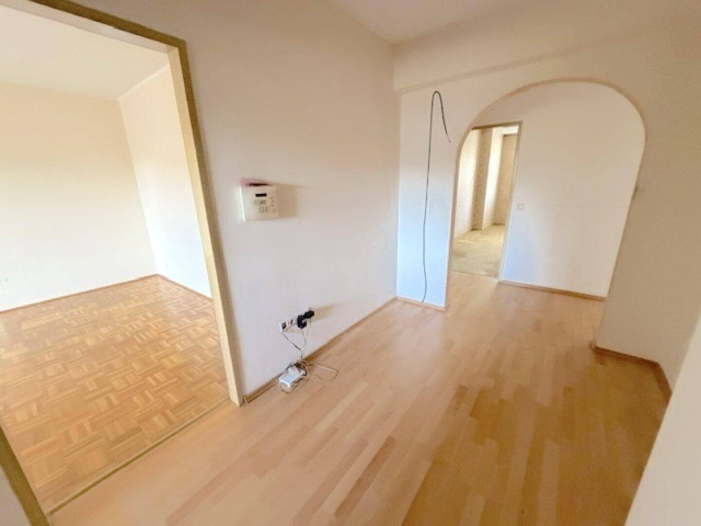 Heller Flur mit Holzboden und einem Bogen, der zu weiteren Räumen führt.