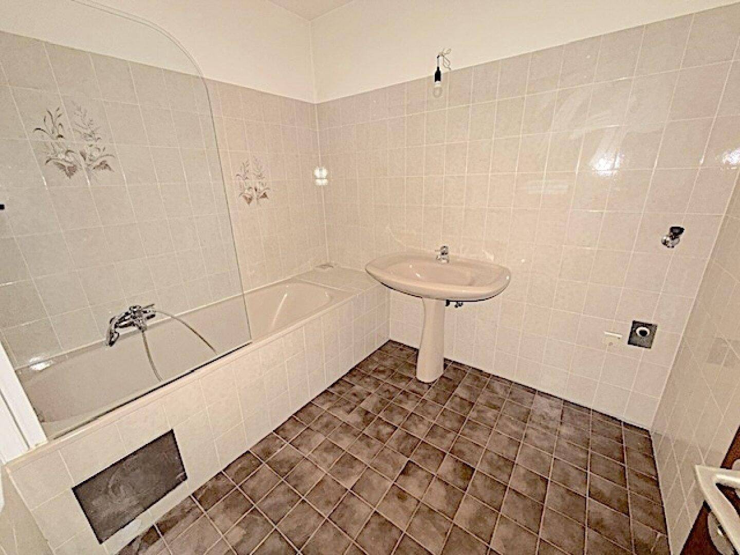 Badezimmer im 80er-Jahre-Stil mit Badewanne und Standwaschbecken.