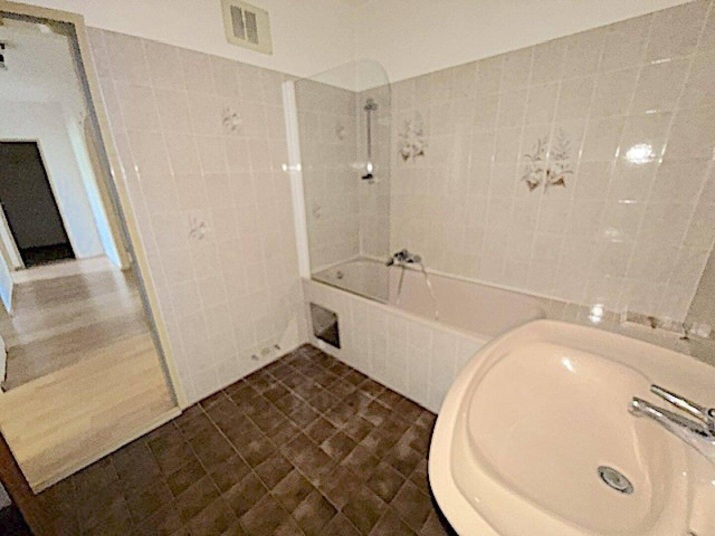 Badezimmer im 80er-Jahre-Stil mit Badewanne und rosa Waschbecken.