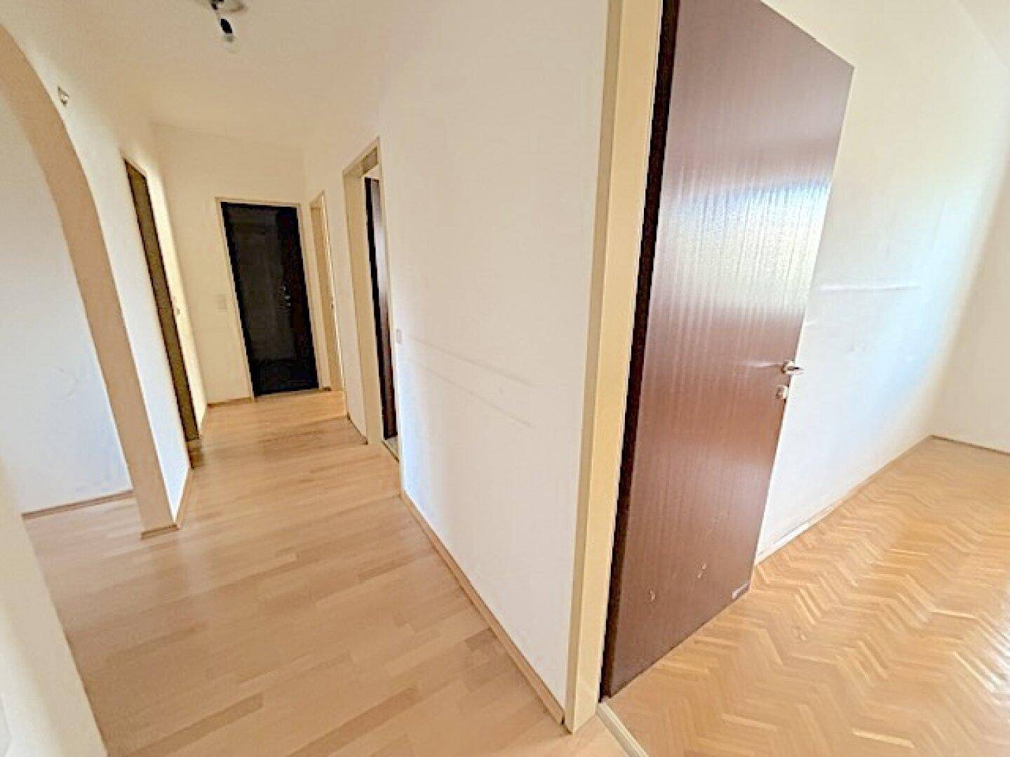 Langer Flur mit Holzboden, der verschiedene Räume der Wohnung verbindet.