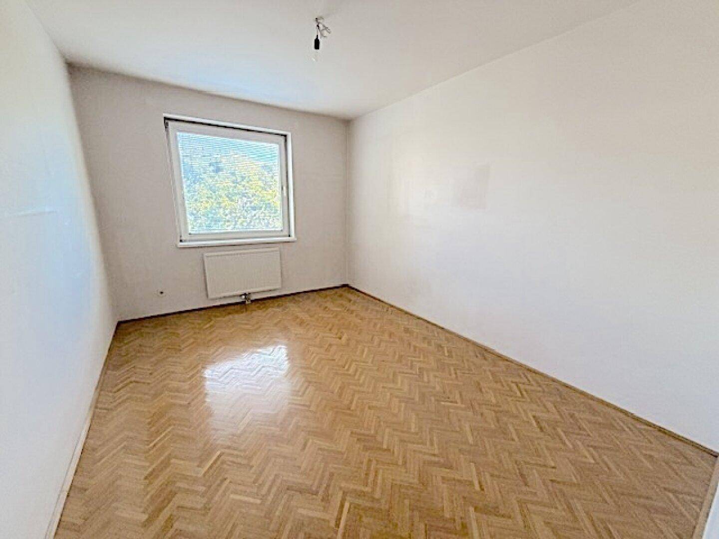 Helles Zimmer mit Holzboden und Fenster, ideal als Schlaf- oder Arbeitszimmer.