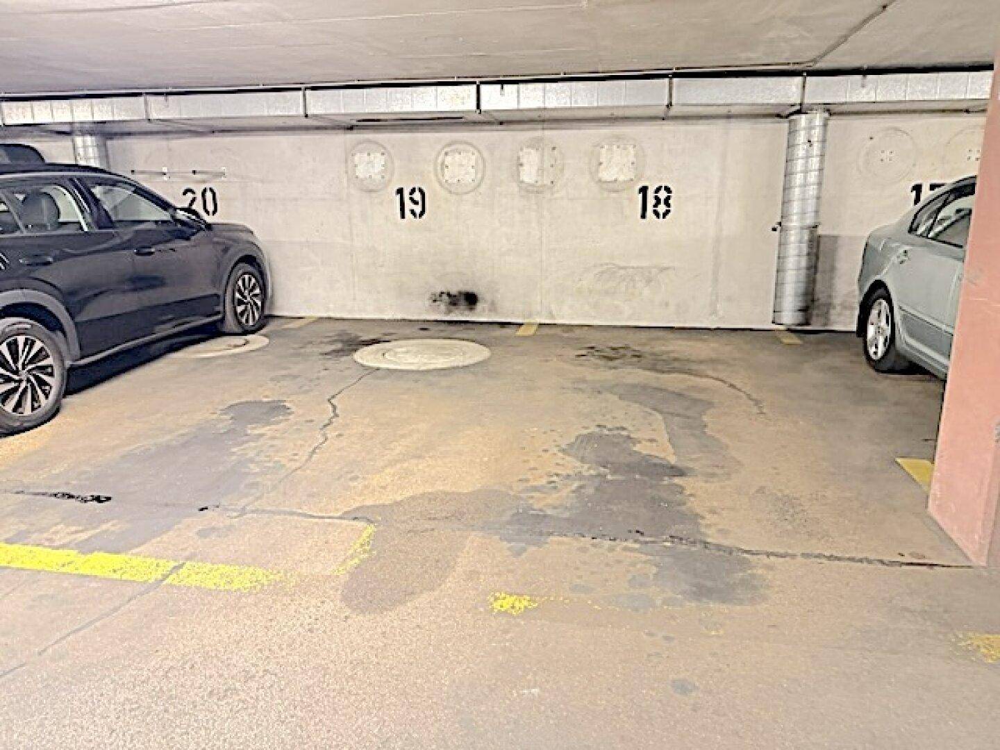 Tiefgaragenstellplatz mit Betonwänden und nummerierten Parkplätzen in einem Mehrfamilienhaus.