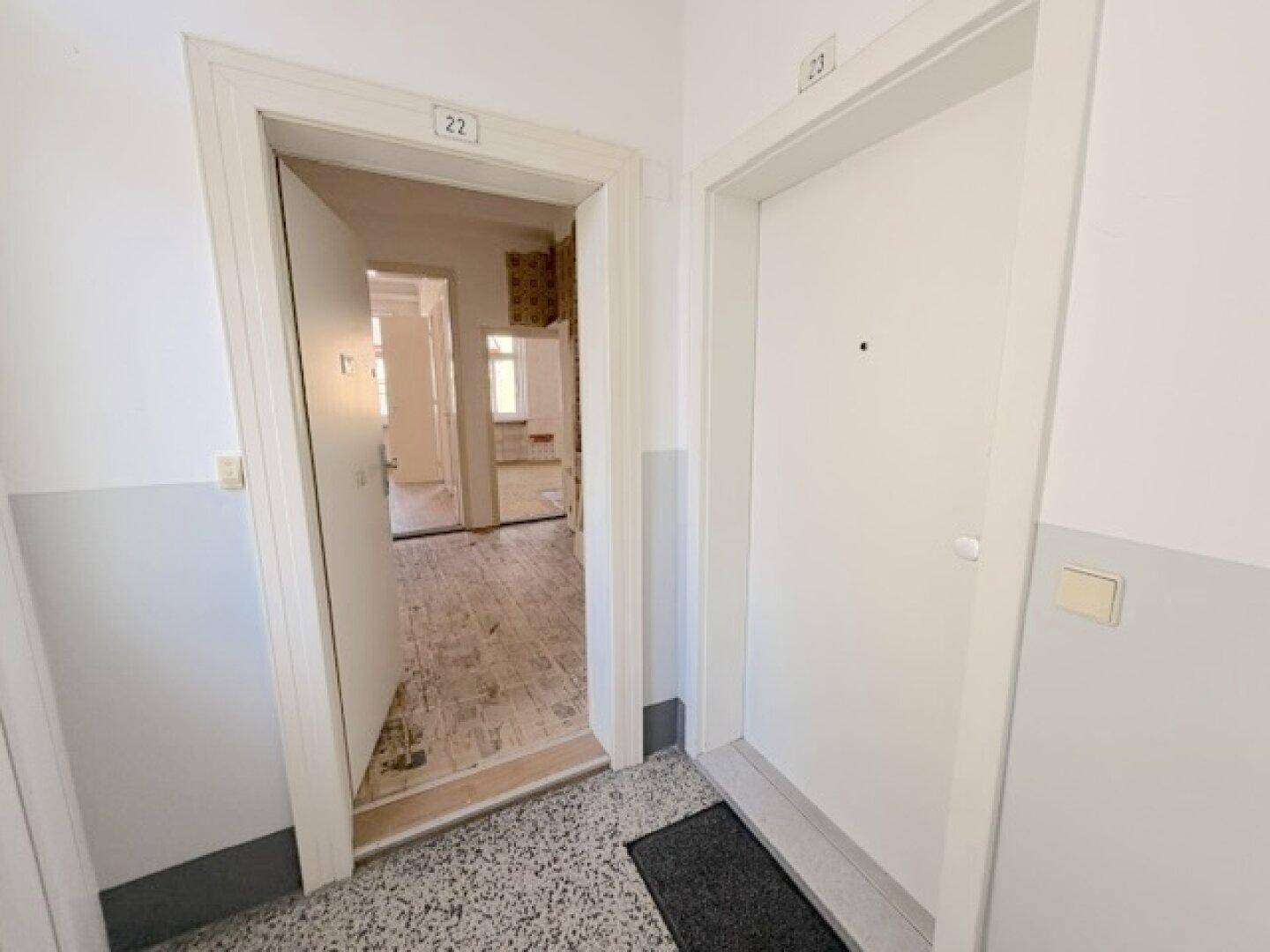 Eingangsbereich einer Wohnung mit Terrazzoboden und Blick in weitere Räume.