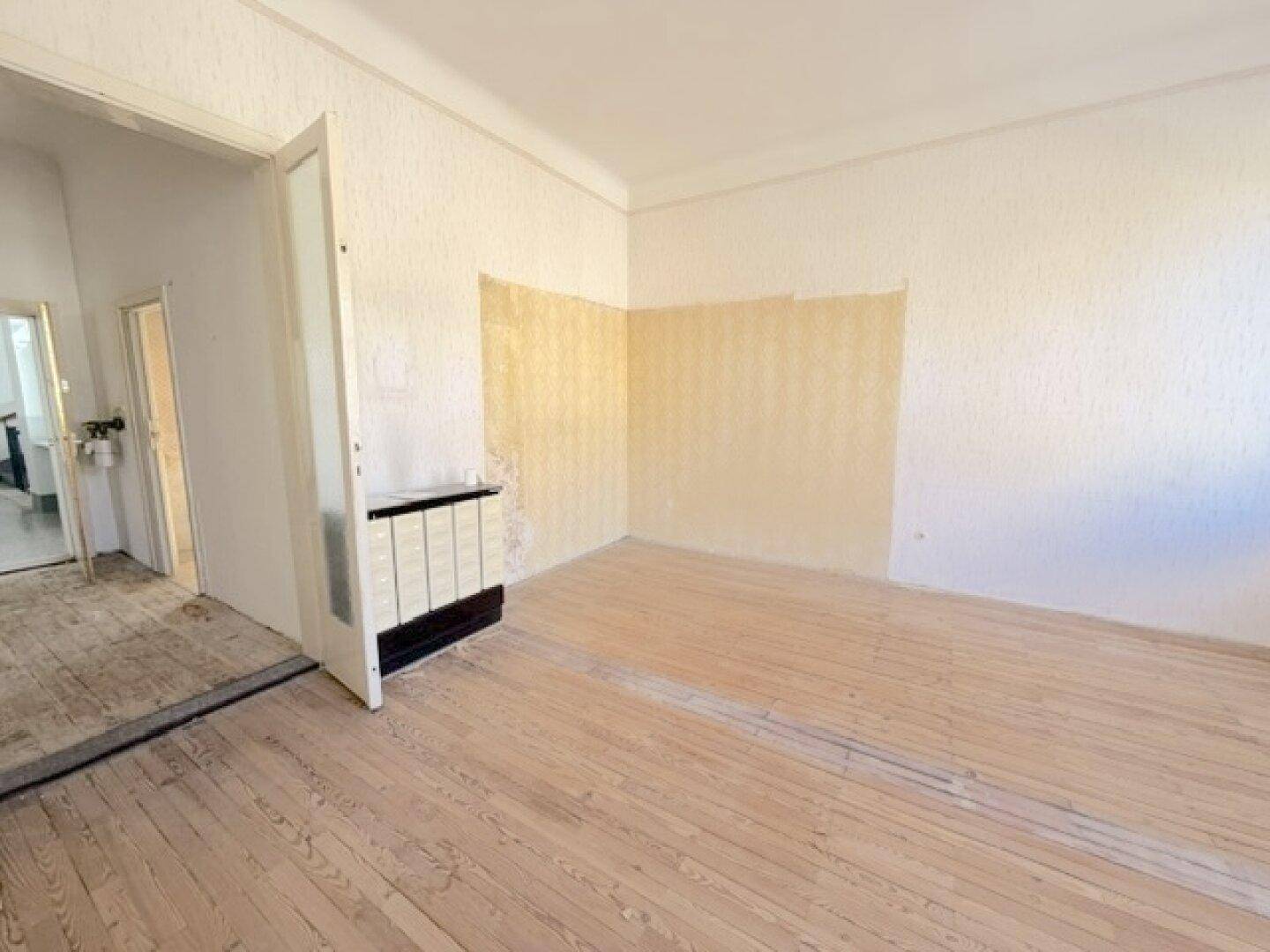 Helles Zimmer mit abgezogenen Holzdielen und einem alten Kachelofen.