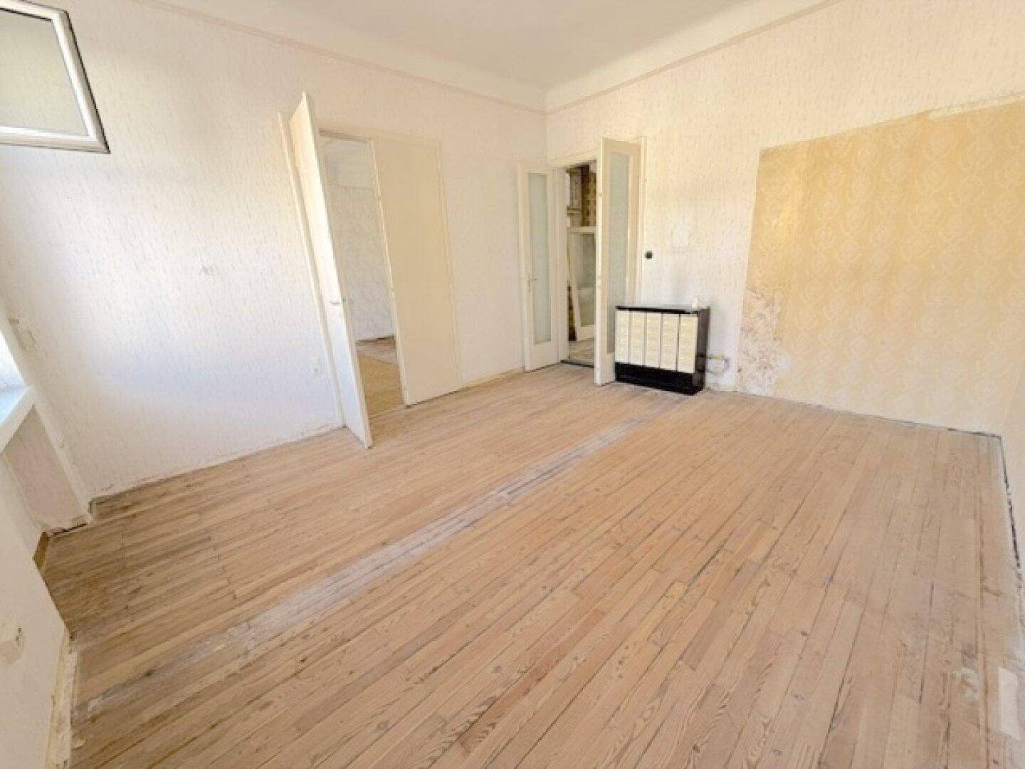 Geräumiges Zimmer mit Holzdielenboden und traditionellem Kachelofen, bereit zur Gestaltung.