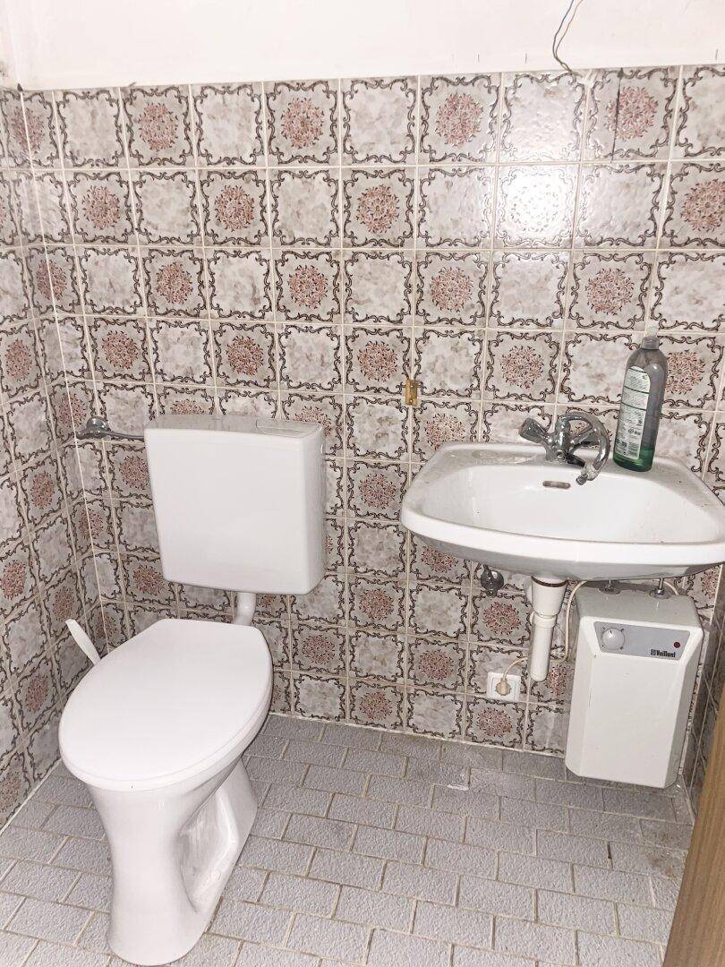 Gästetoilette mit WC, Waschbecken und auffälligen gemusterten Wandfliesen.