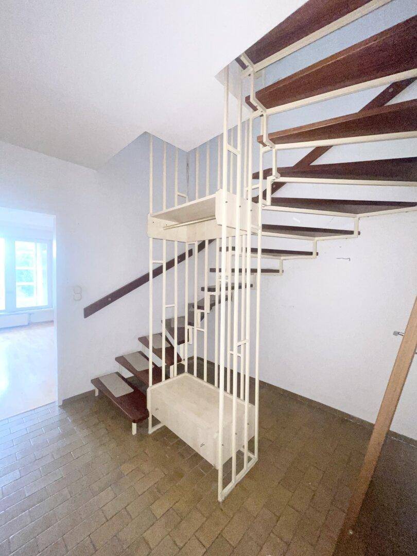 Flur mit einer eleganten Wendeltreppe, die in die obere Etage führt, und Fliesenboden.