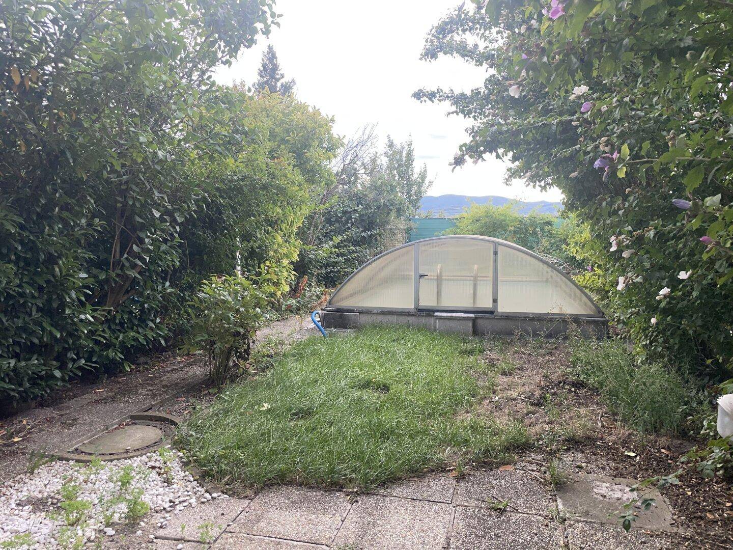 Garten mit überdachtem Pool und viel Grün, das auf Pflege wartet.
