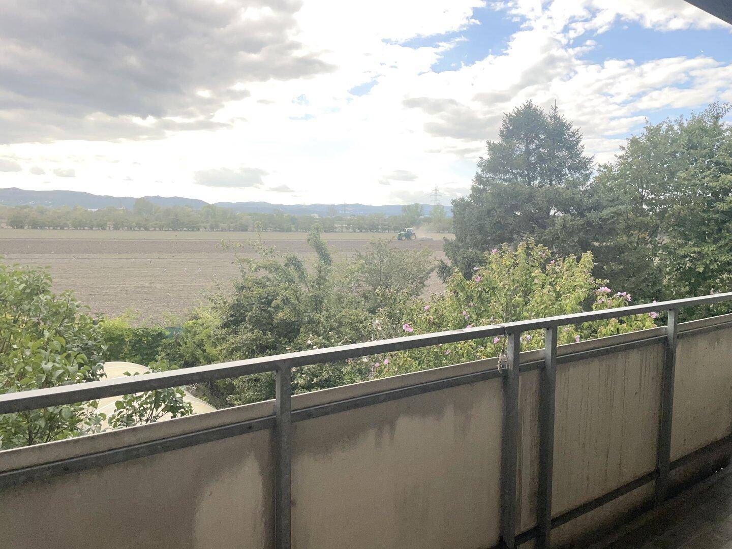 Balkon mit Metallgeländer und weitem Blick über Felder und die umliegende Landschaft.