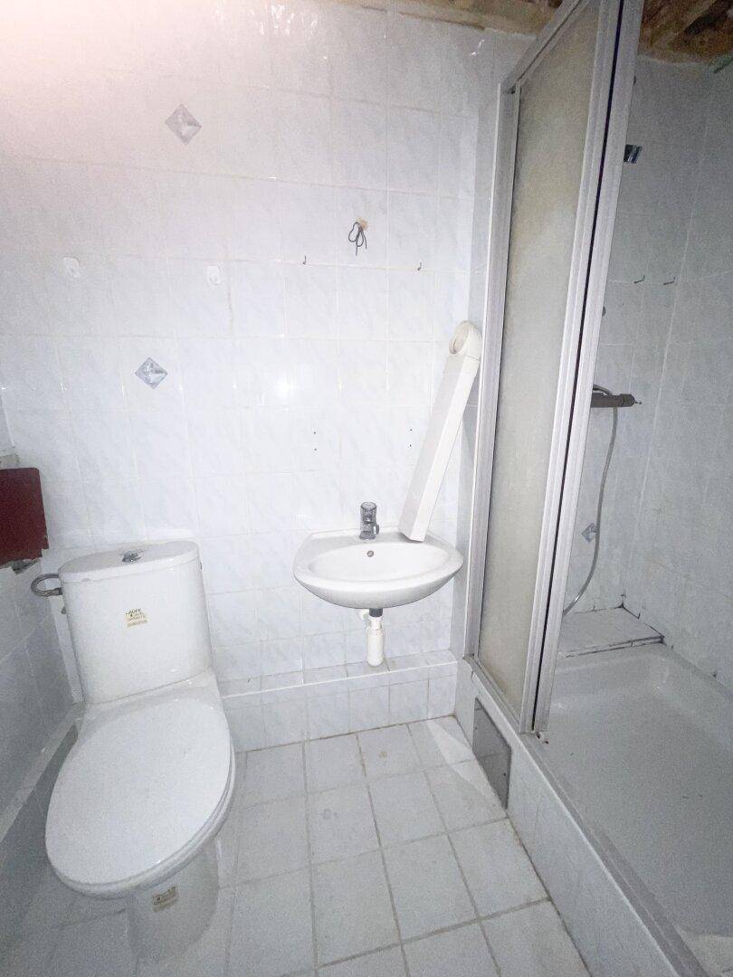 Funktionales Badezimmer mit Duschkabine, WC und Waschbecken, komplett gefliest in Weiß.