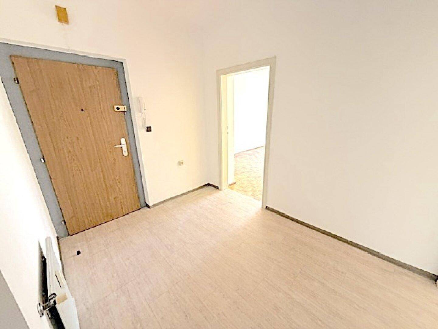 Heller Flur mit Eingangstür und Blick in einen weiteren Raum der Wohnung, praktisch und geräumig.
