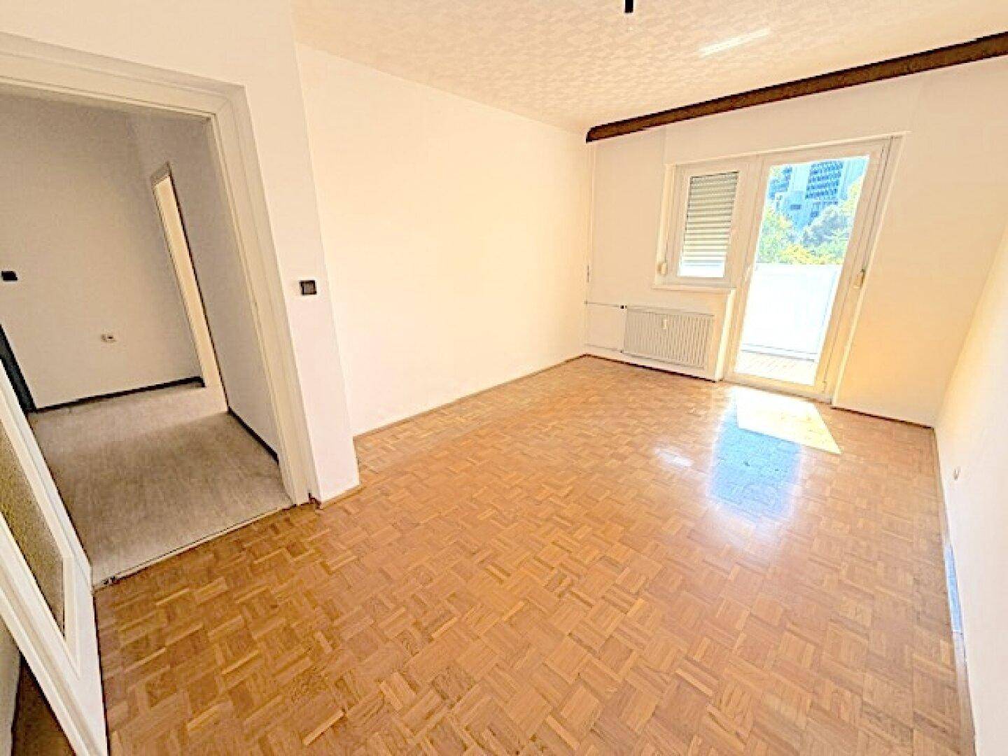 Heller Raum mit Parkettboden und Türöffnung zu einem weiteren Bereich der Wohnung, vielseitig nutzbar.