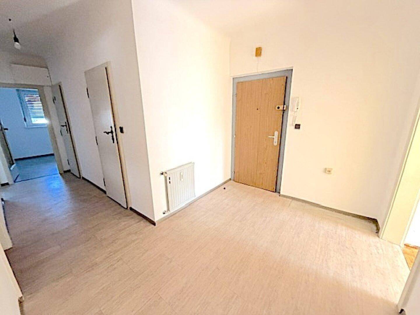 Eingangsbereich mit hellem Boden und Zugang zu verschiedenen Zimmern der Wohnung, funktional und einladend.