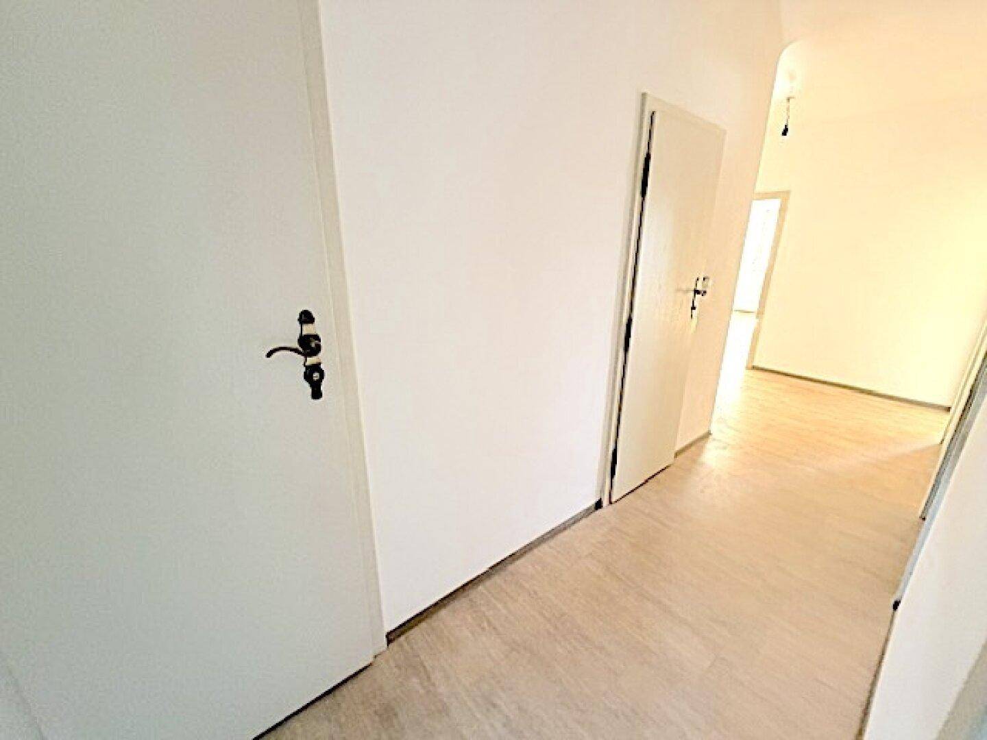 Langer Flur mit mehreren Türen, die zu den verschiedenen Räumen der Wohnung führen, hell und funktional.
