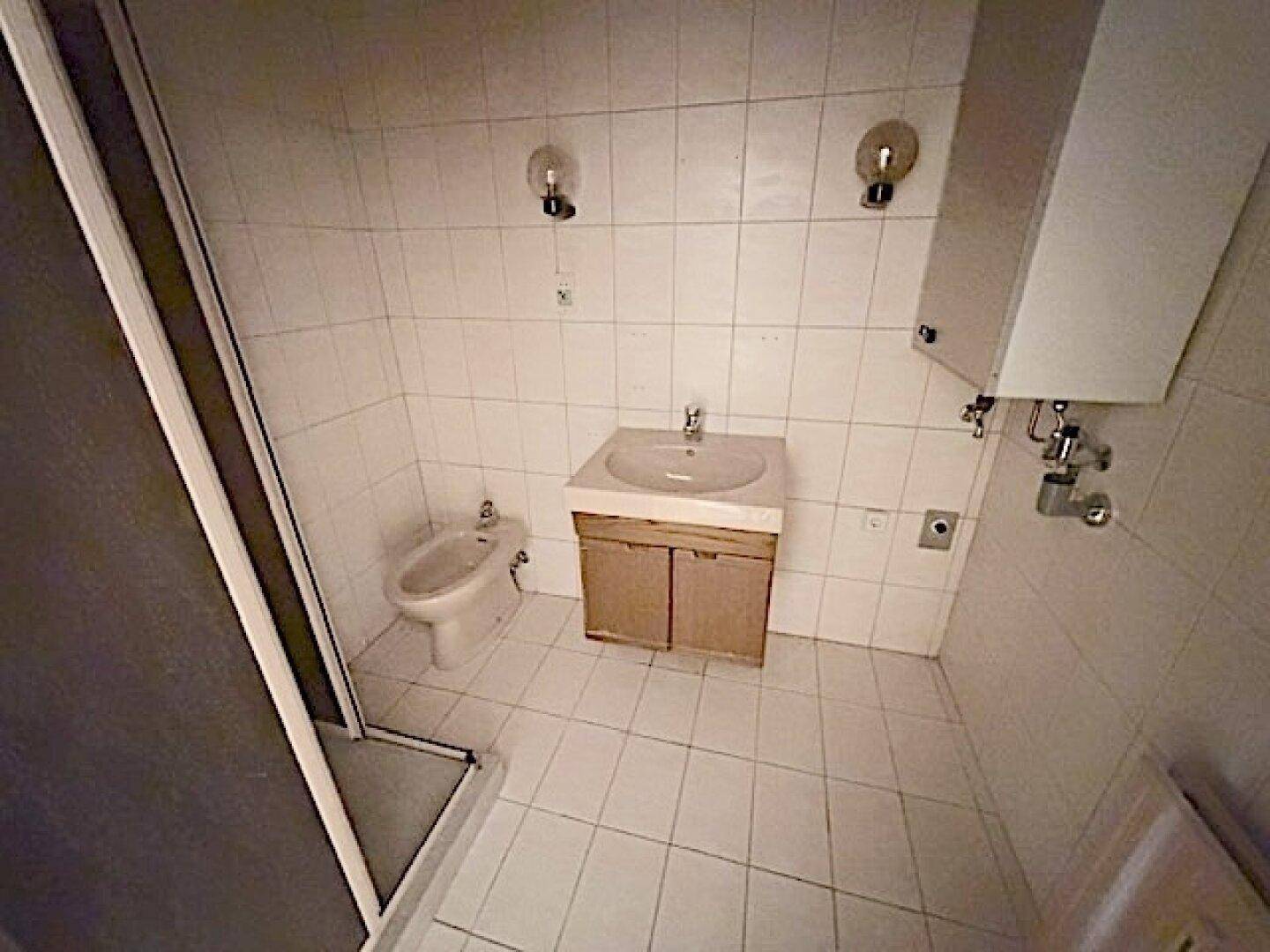 Badezimmer mit Dusche, Waschbecken und Bidet, komplett gefliest in hellem Ton, praktisch und gepflegt.