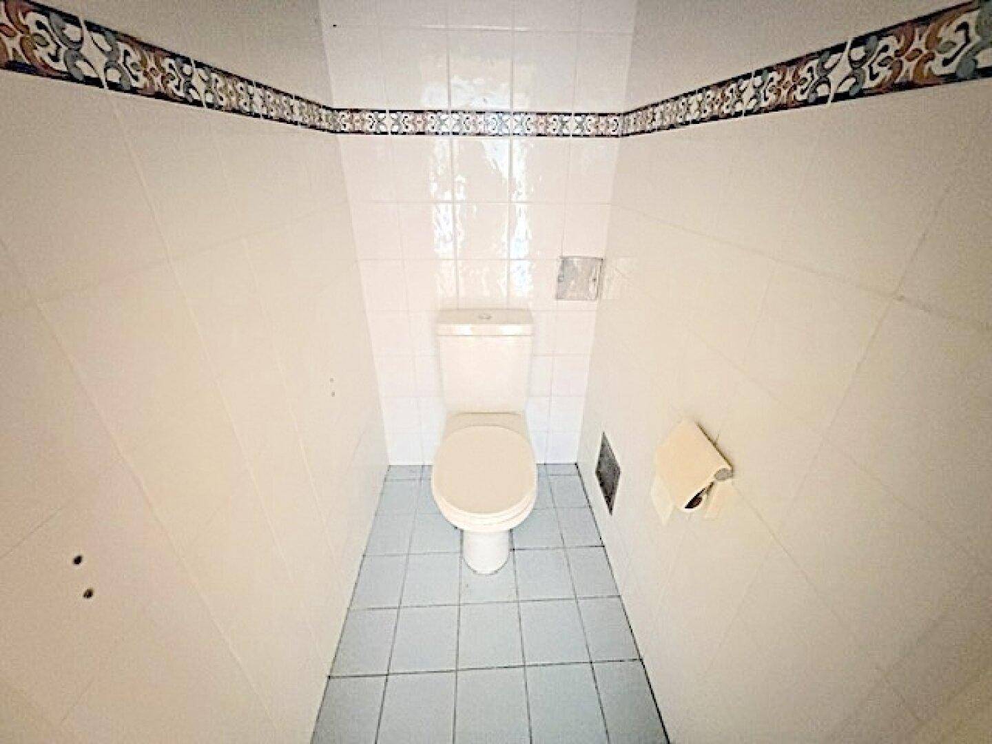 Separates WC mit Fliesenboden und Wandfliesen in hellem Design, sauber und funktional.