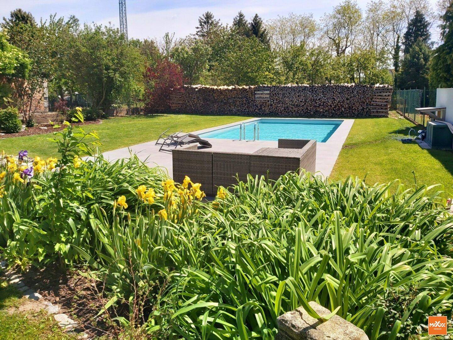 Großer Garten mit Swimmingpool, Liegeflächen und umgebender Bepflanzung.
