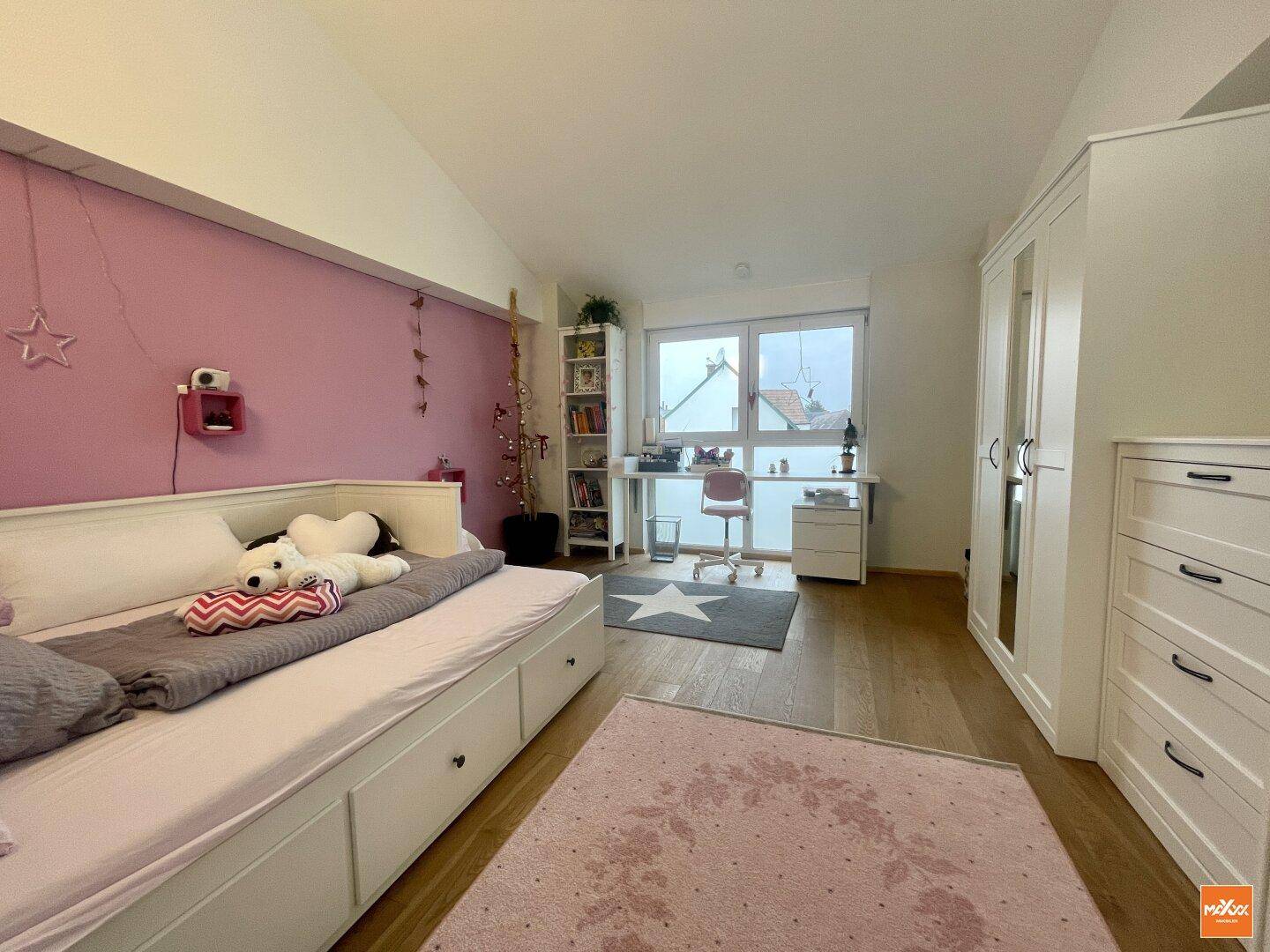 Kinderzimmer mit Holzboden, Schreibtisch und Fenster mit Blick nach draußen.