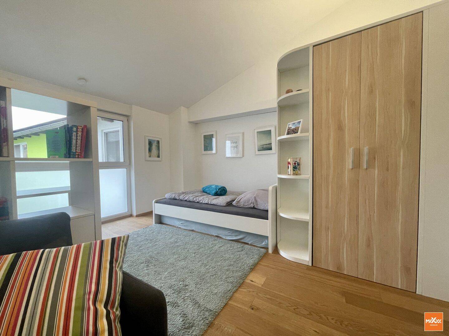 Kinderzimmer mit Holzboden, Einbauschränken und Fenster für natürliches Licht.