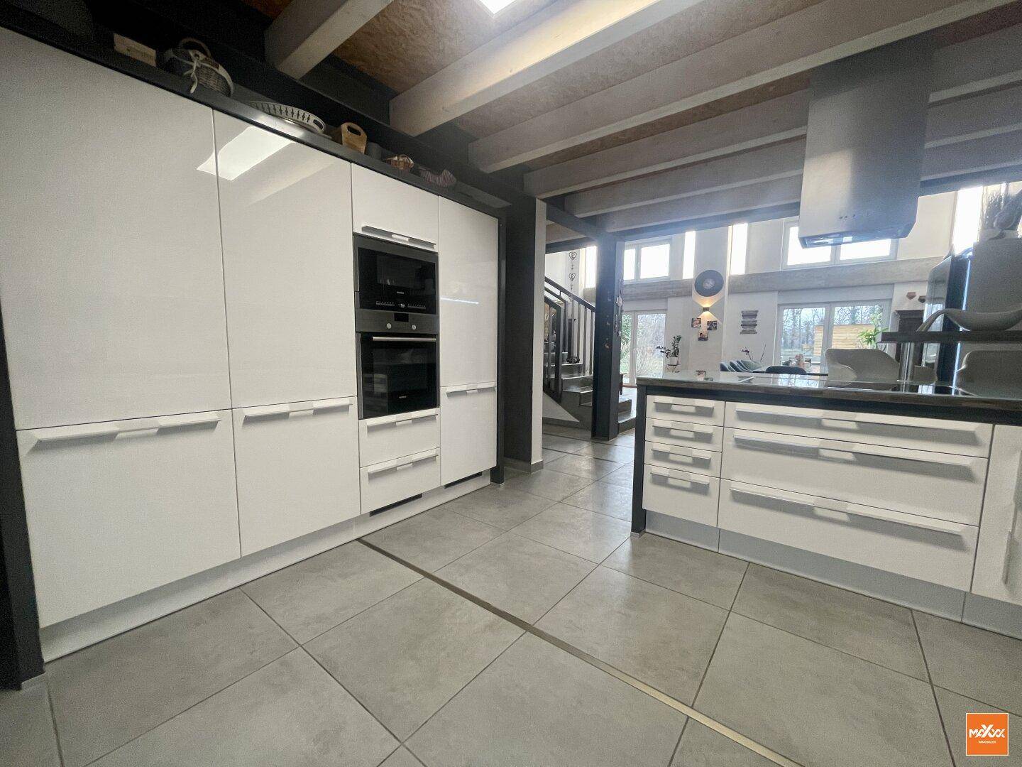 Hochglanz-Einbauküche mit integriertem Backofen und Mikrowelle, offen zum Wohnbereich.