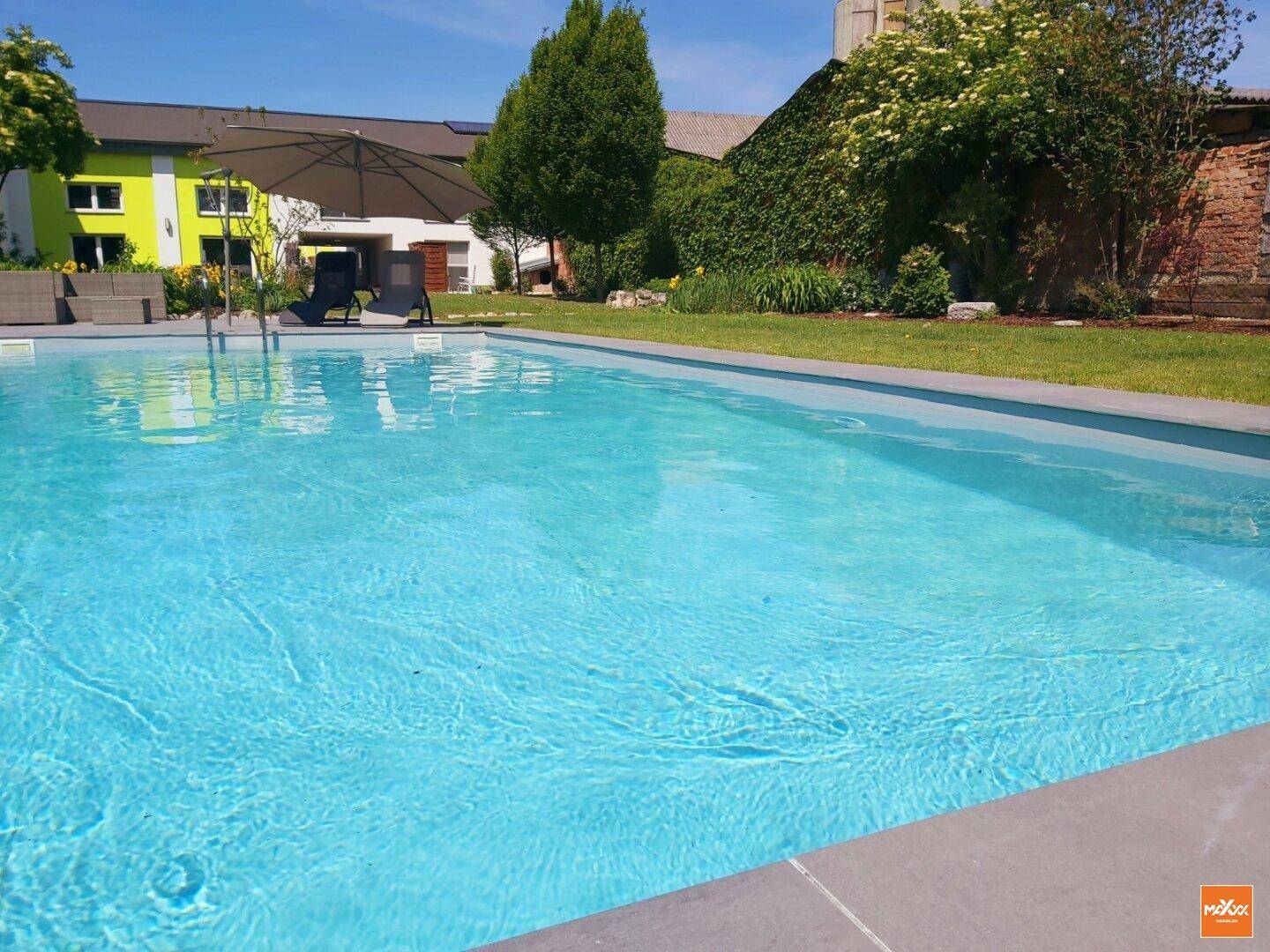 Erfrischender Swimmingpool im Garten mit klarem Wasser und Liegestühlen.