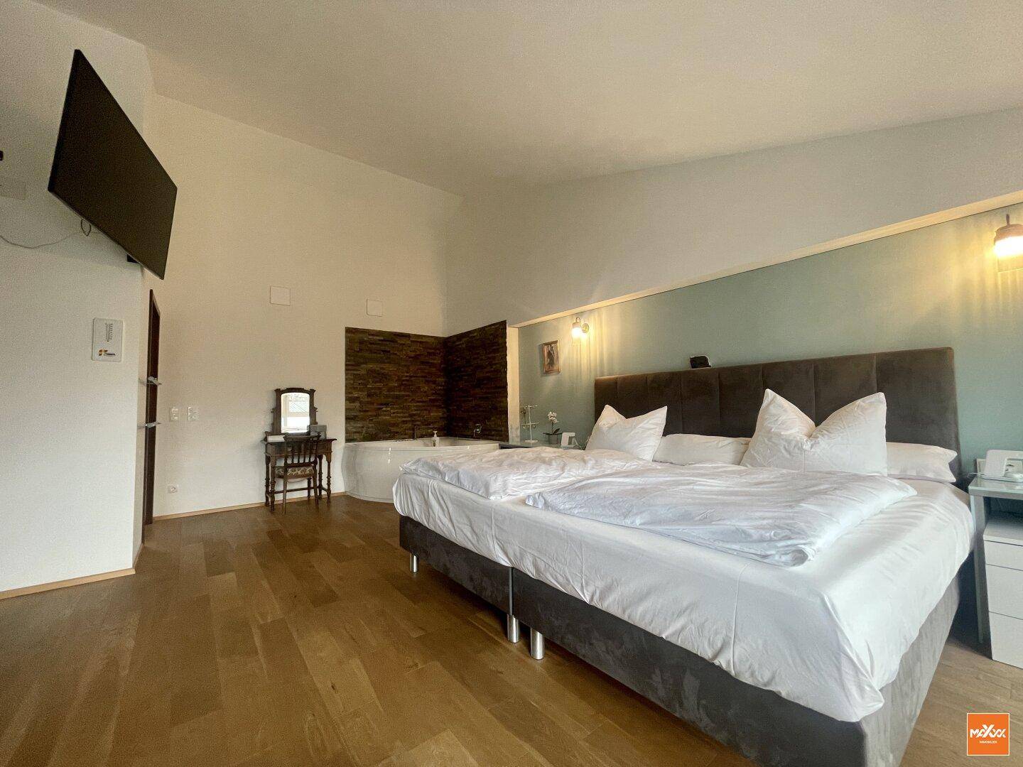 Schlafzimmer mit Doppelbett, Holzboden und dekorativer Wandverkleidung.