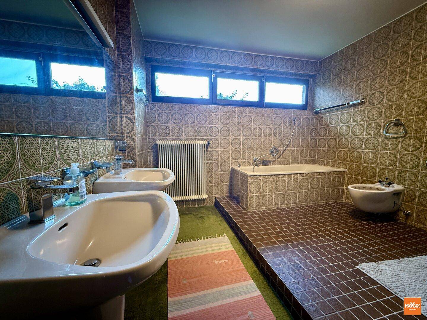 Badezimmer mit zwei Waschbecken, Badewanne, Bidet und Fenster für natürliche Belüftung.