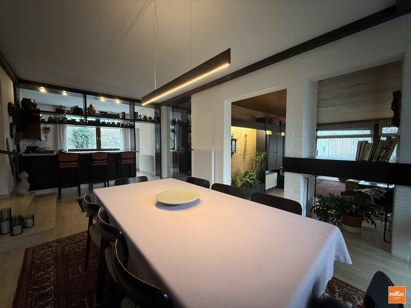 Heller Essbereich mit großem Esstisch, moderner Deckenleuchte und Blick in den angrenzenden Wohnbereich.