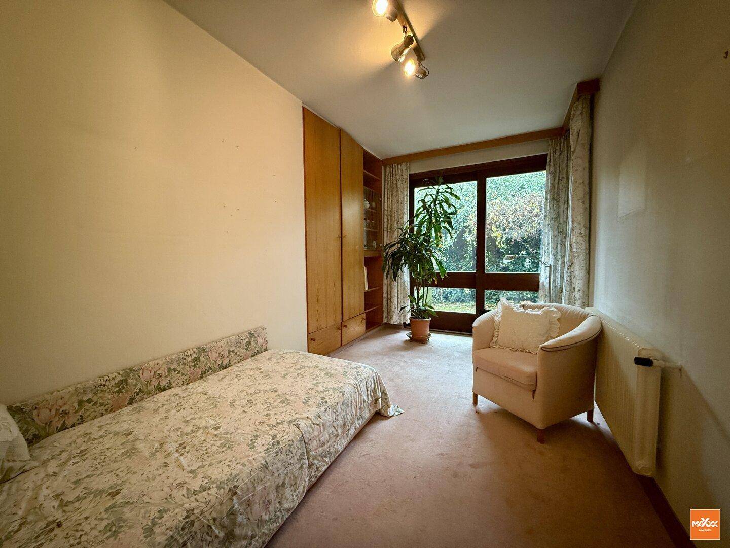 Helles Schlafzimmer mit Einzelbett, Teppichboden und Zugang zu einem Fenster mit Blick ins Grüne.