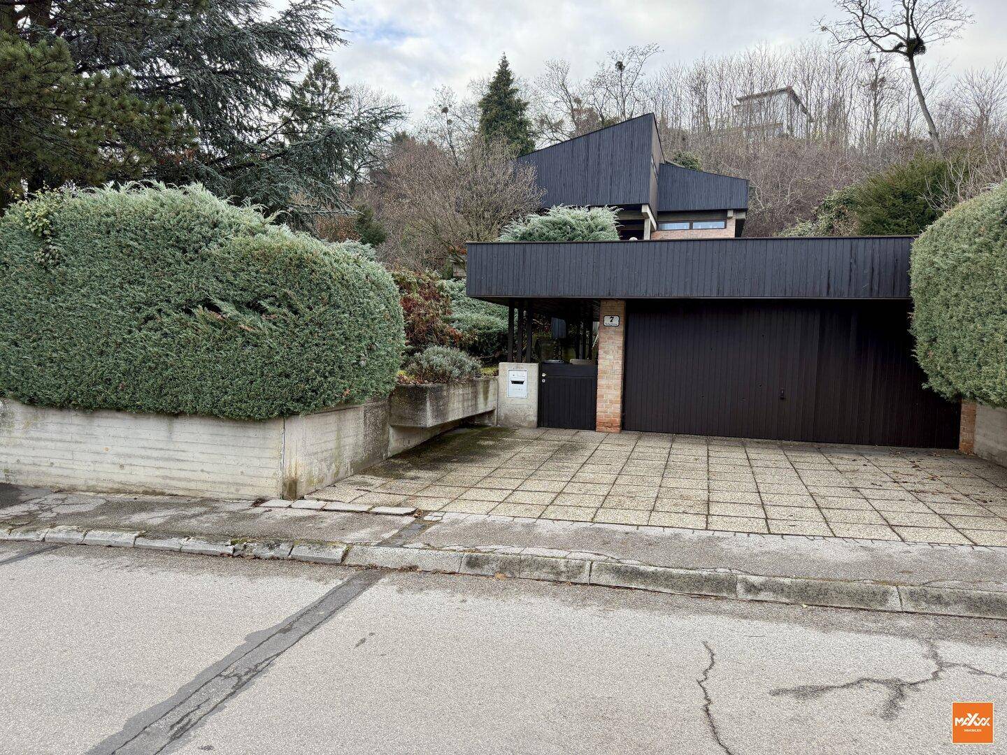 Zufahrt zum Haus mit Doppelgarage und gepflastertem Vorplatz.