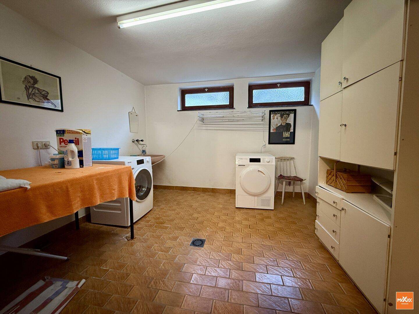 Praktischer Waschraum im Untergeschoss mit Waschmaschine, Trockner und Fenster.