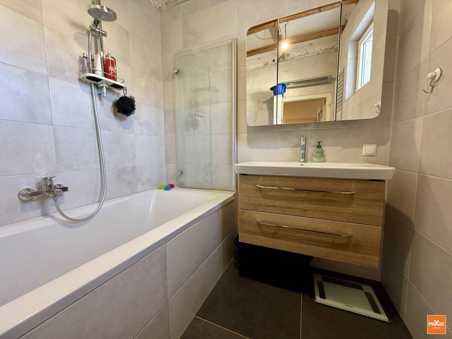 Modernes Badezimmer mit Badewanne, Waschtisch und hellen Fliesen.