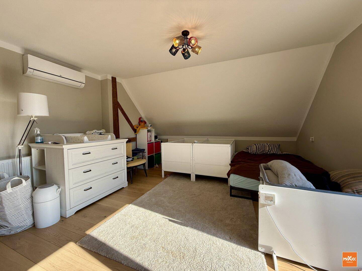 Helles Kinderzimmer im Dachgeschoss mit Dachschräge, Klimaanlage und Holzboden.