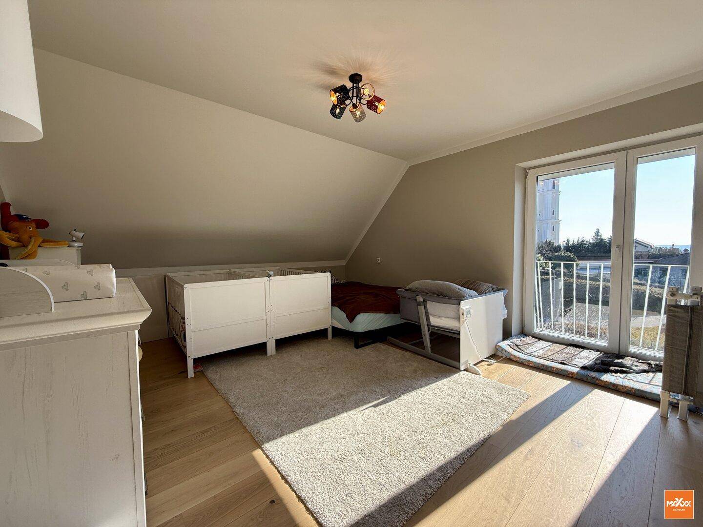 Lichtdurchflutetes Kinderzimmer mit französischem Balkon, Dachschräge und Holzboden.
