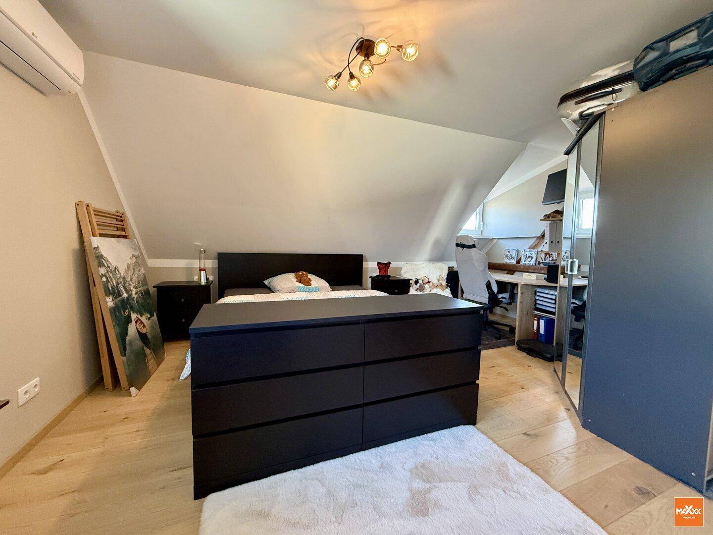 Geräumiges Schlafzimmer im Dachgeschoss mit Dachschräge, Klimaanlage und Holzboden.