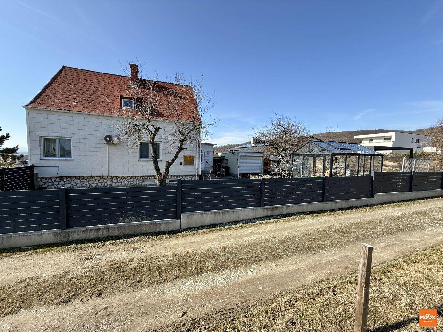 Einfamilienhaus mit Garten, Zaun und weitem Blick über die ländliche Umgebung.