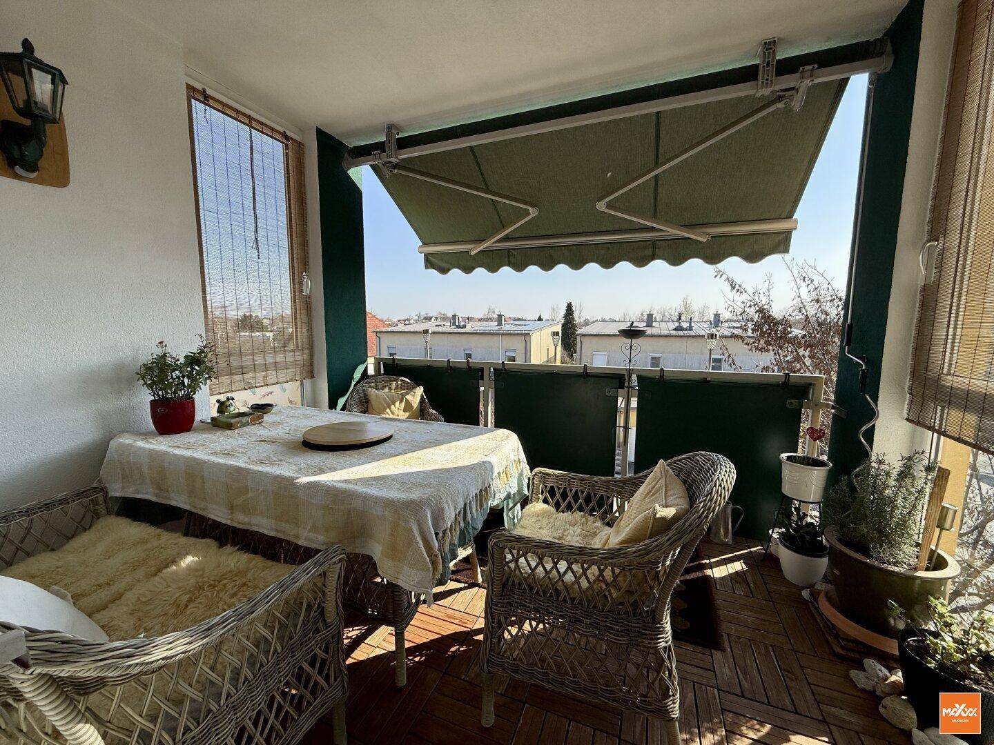 Sonniger Balkon mit gemütlicher Sitzecke und Markise, ideal zum Entspannen.