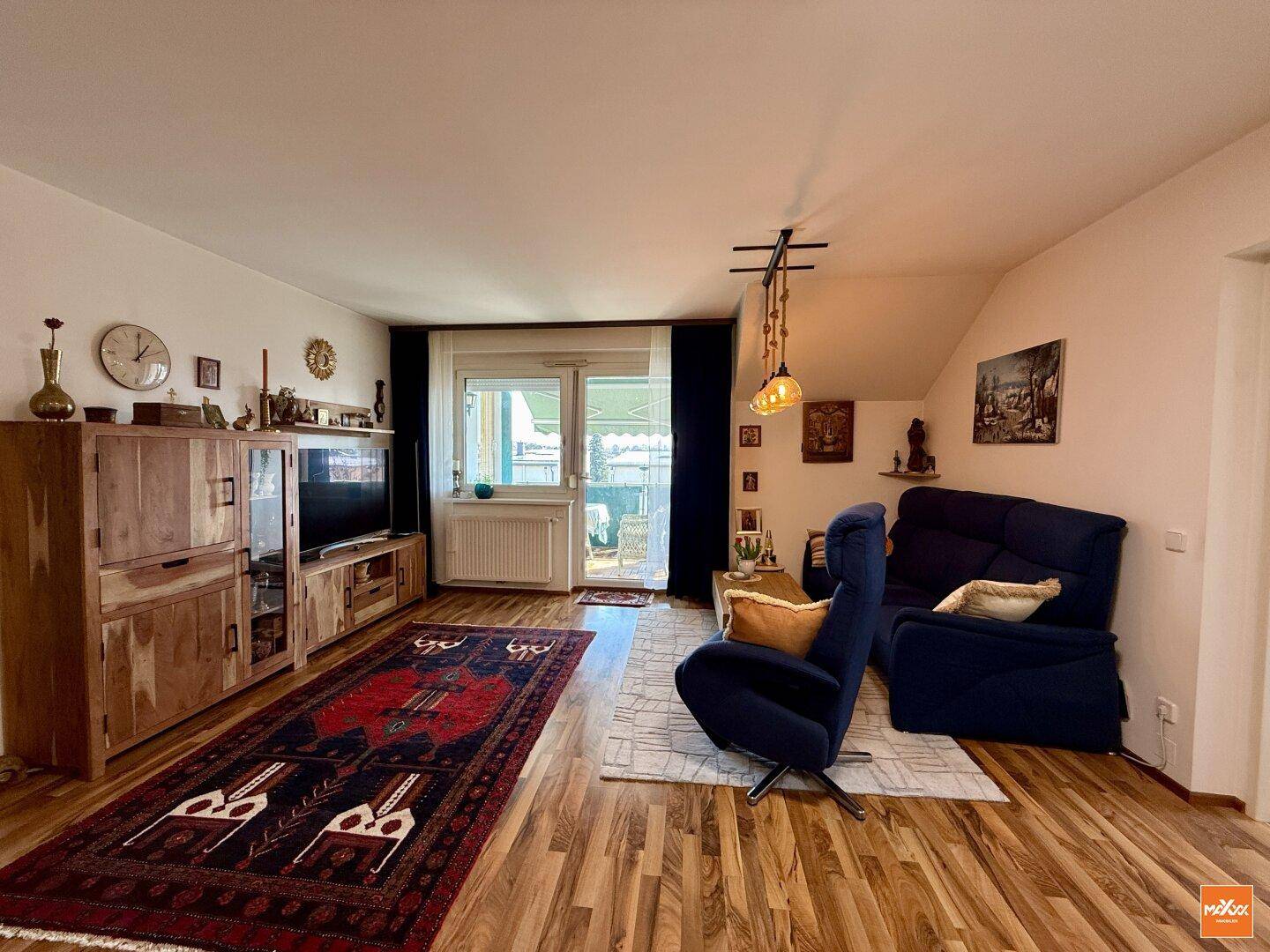 Geräumiges Wohnzimmer mit Holzboden, gemütlicher Sitzecke und Zugang zum Außenbereich.
