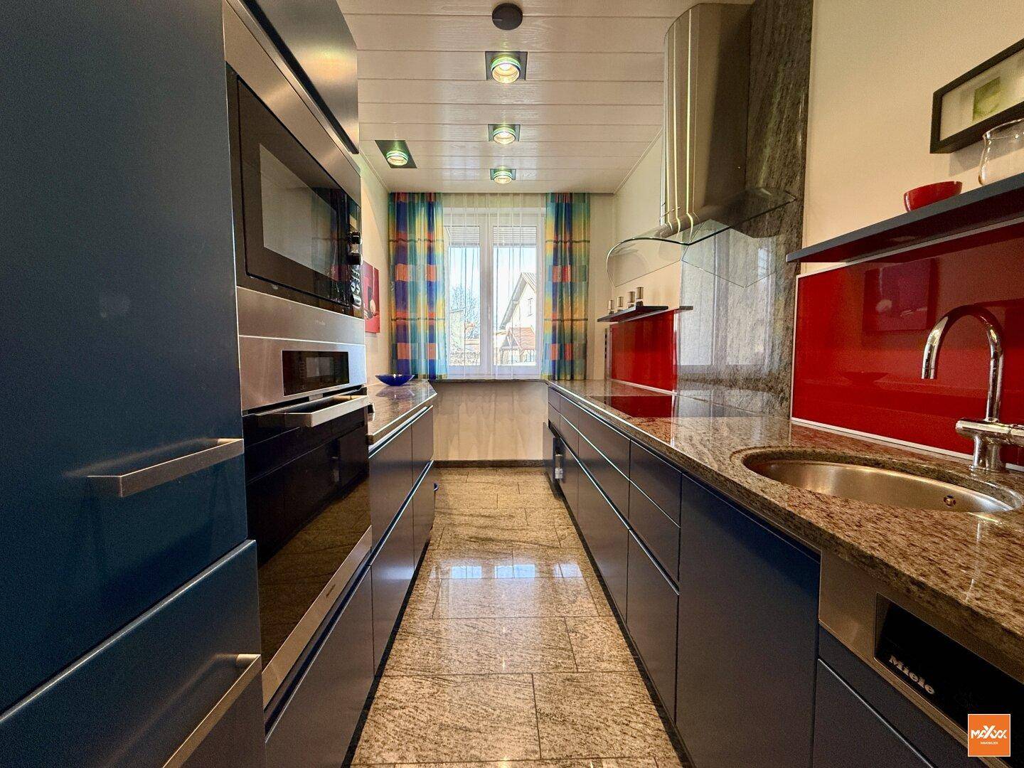 Moderne Küche mit blauen Schränken, Granitarbeitsplatten und integrierten Geräten.