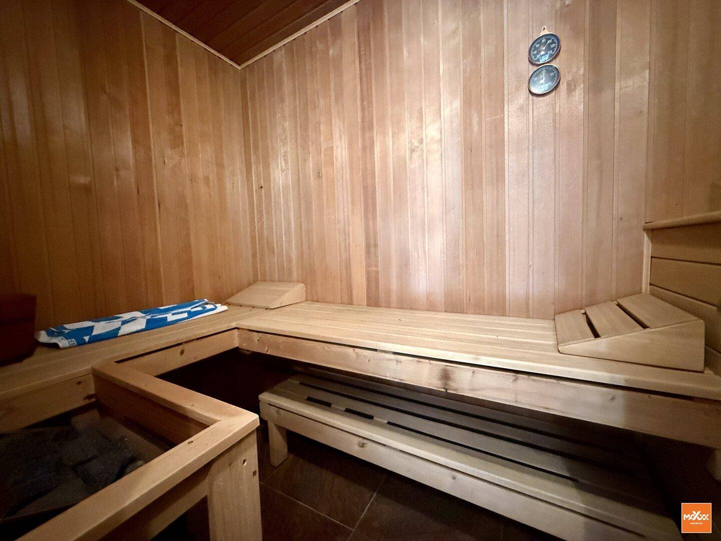 Gemütliche Holzsauna mit Bänken und Temperaturanzeige für Entspannung.