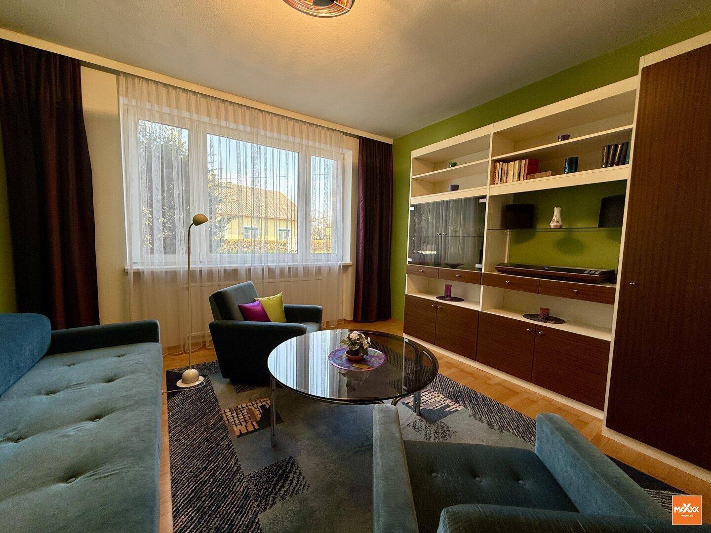 Wohnzimmer mit Einbauregalen, großem Fenster und gemütlicher Sitzecke.